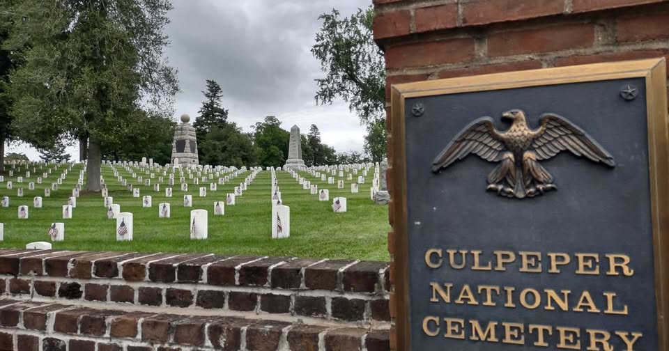 brick wall with "Culpeper National Cemetery" written on a plaque and graves in the background